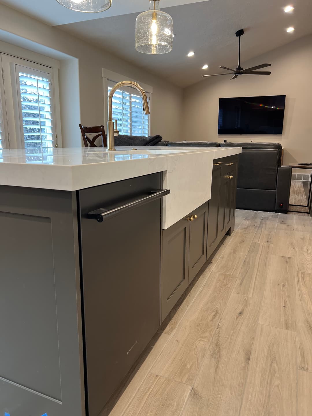 Modern kitchen featuring an island with a white countertop, gray cabinetry, and stylish pendant lights.