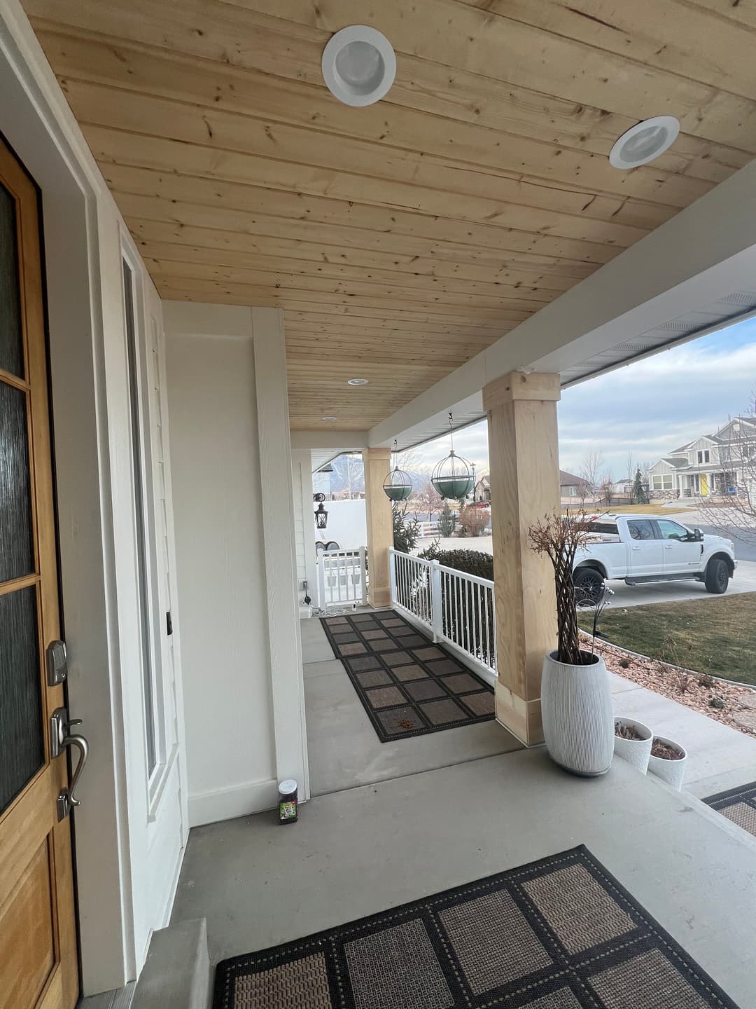 Welcoming front porch with wooden ceiling, decorative planters, and outdoor lighting.