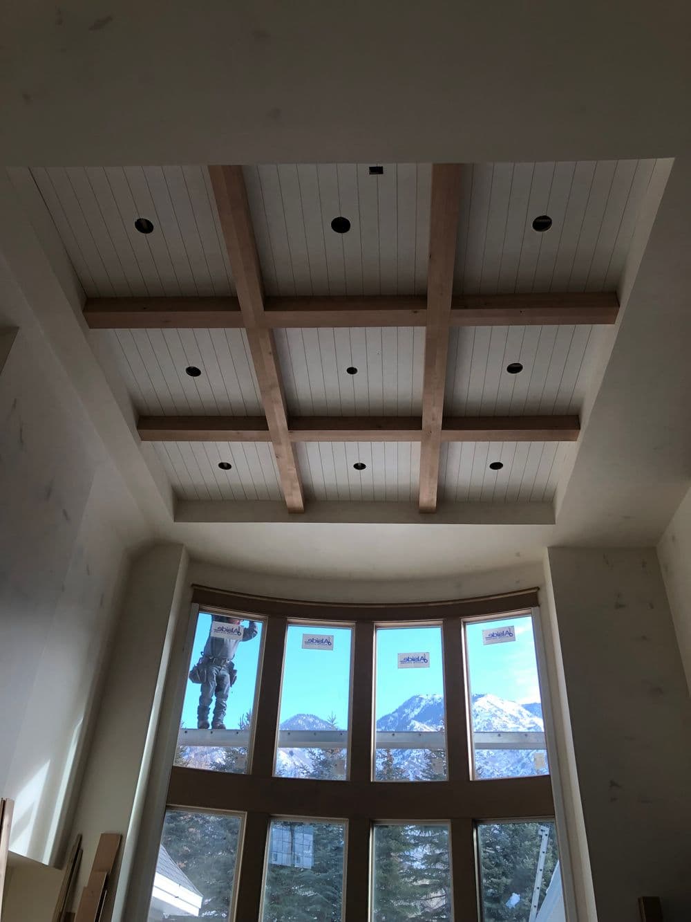 Modern interior featuring a coffered ceiling with wooden beams and large windows showcasing mountain views.