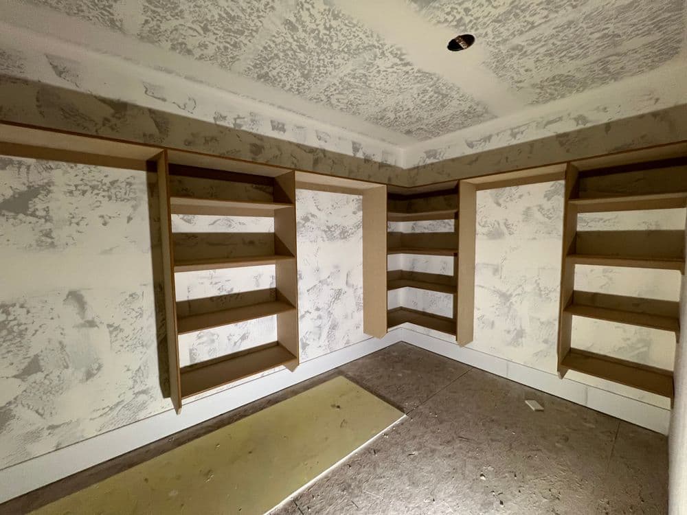 Empty room with unfinished walls and built-in shelves, awaiting design completion.