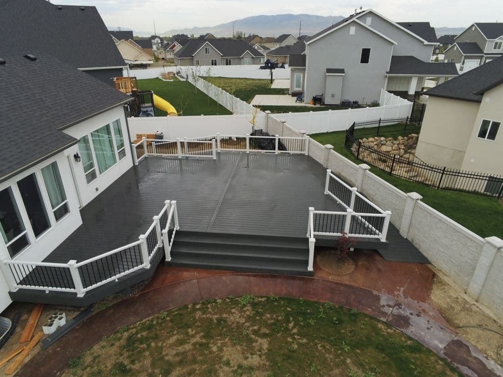 Aerial view of a spacious modern deck with white railings and landscaped backyard.