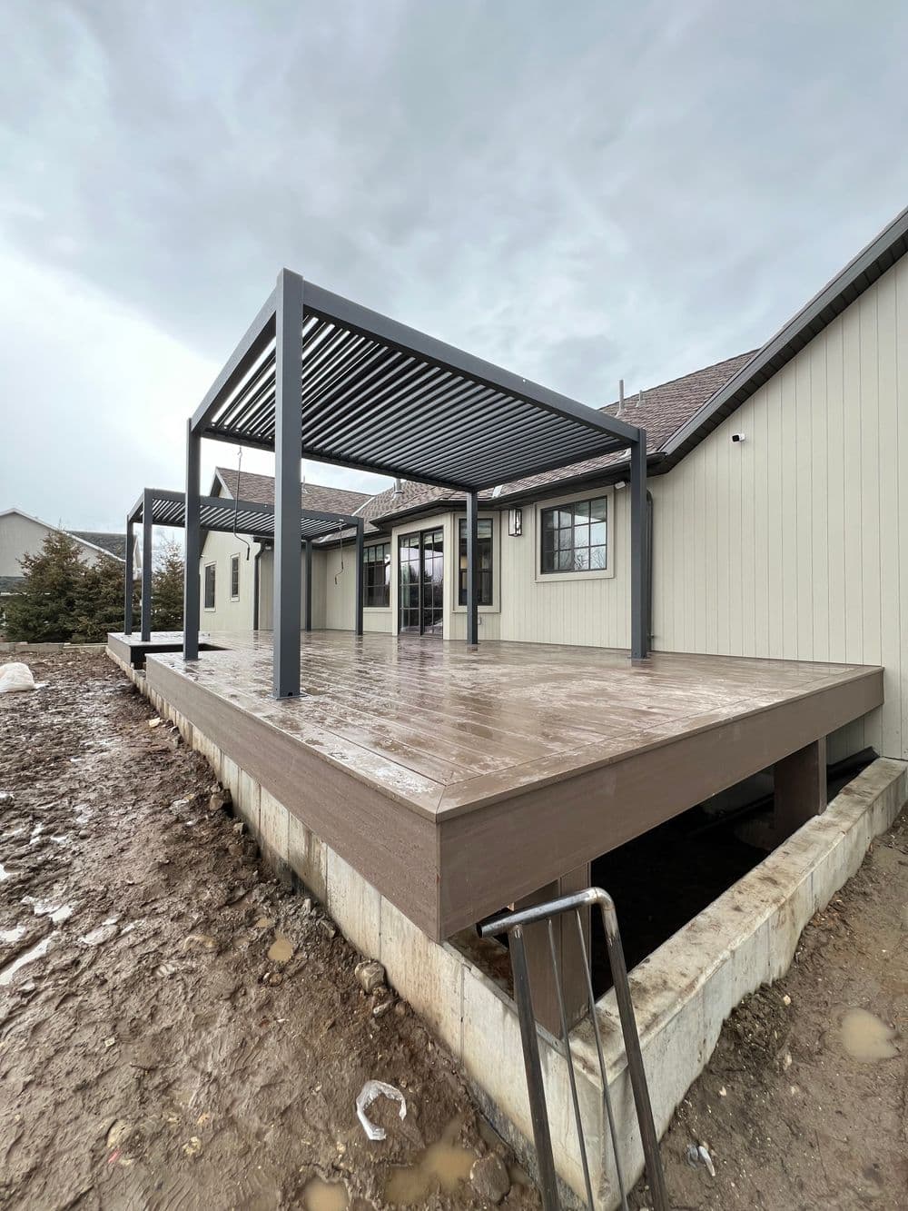Modern outdoor deck with pergola, newly constructed, surrounded by bare landscape.